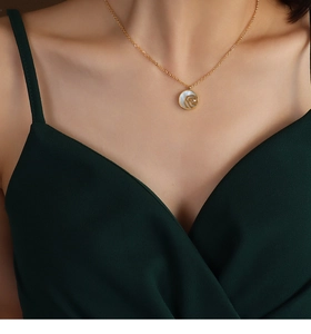 Close-up of gold rose pendant necklace with white mother of pearl on a female model