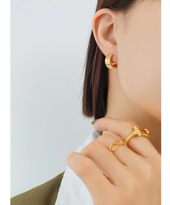 Detailed shot of 18K gold plated C-shape zircon earrings and minimalist rings on model