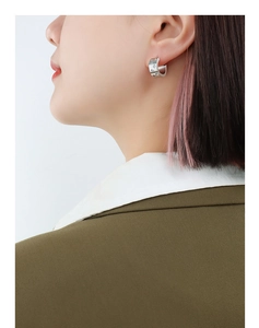 Close-up of geometric C-shaped earrings with star engraving worn by a model
