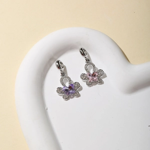 Macro detail of silver butterfly charms with purple and pink crystals in heart tray