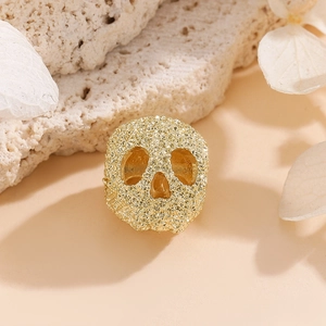 Gros plan d'une breloque tête de mort dorée texturée pour la création de bijoux DIY