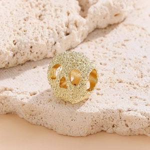 Perle de crâne dorée pour bijoux DIY avec texture mate sur fond de pierre naturelle