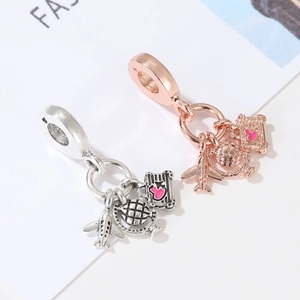 Travel charms with airplane, globe, and pink heart suitcase in silver and rose gold finish