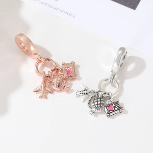 Detailed view of travel charms featuring a plane, globe, and pink heart suitcase charms