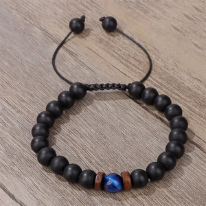 Dettaglio macro del bracciale in occhio di tigre intrecciato a mano su superficie in legno