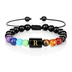 Detalle macro de la pulsera de cuentas de piedra con la letra R dorada en cuenta cuadrada
