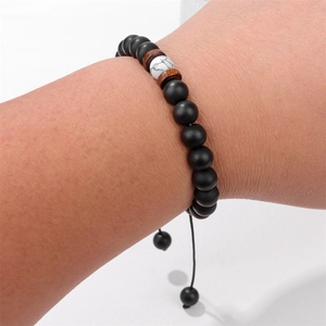 Dettaglio di perline occhio di tigre opache e distanziali in legno su bracciale intrecciato