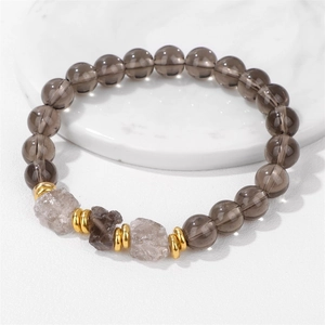 Bracciale di perline in pietra naturale con quarzo fumé e distanziatori dorati su marmo