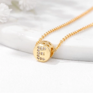Macro shot of gold-plated letter E pendant with crystal inlay and heart cut-out detail