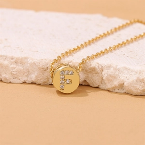 Macro shot of gold-plated pendant with sparkling cubic zirconia letter F on O-chain