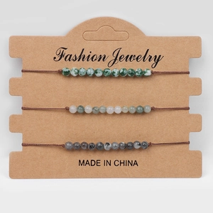 Détail de trois bracelets tissés en perles de pierre naturelle verte et grise sur carte