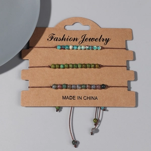 Vue rapprochée de trois bracelets de perles tissés main sur une carte en kraft