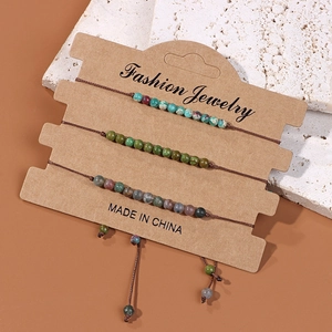 Vue détaillée de trois bracelets en perles tissés à la main sur une carte de présentation