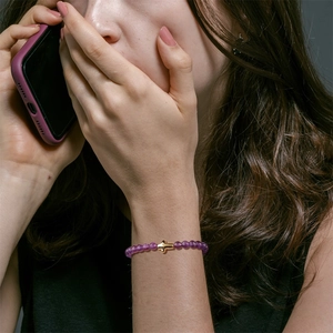 Close-up of 6mm purple stone bead bracelet with a polished gold cross on a model wrist