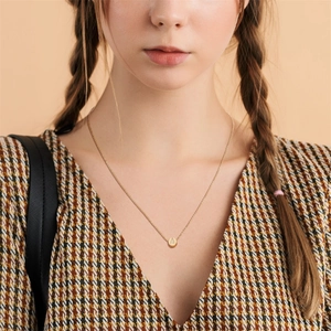 Elegant gold letter A teardrop necklace on a model wearing a plaid V-neck dress