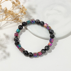 Gros plan du bracelet en perles de pierre sombre avec des cubes arc-en-ciel