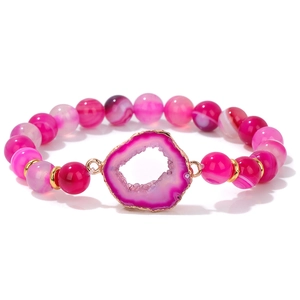 Primer plano de pulsera de cuentas de ágata rosa con colgante de rodaja de cuarzo druzy