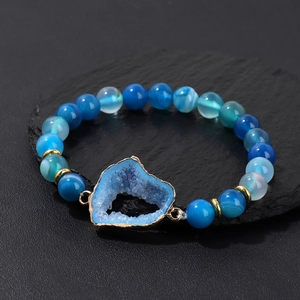 Detalle de pulsera de cuentas de ágata azul con un colgante de geoda de cristal de corazón