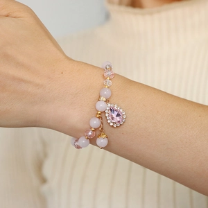 Detail of pink crystal beaded bracelet with teardrop pendant and gold tassel on wrist