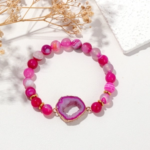 Pulsera de cuentas de ágata rosa con geoda central y borde dorado en fondo blanco