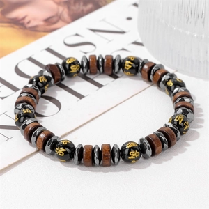 Bracciale elastico con perline nere, distanziali in legno e simboli mantra dorati