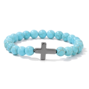 Gros plan du bracelet en perles de pierre bleue avec une croix en métal noir sur fond blanc