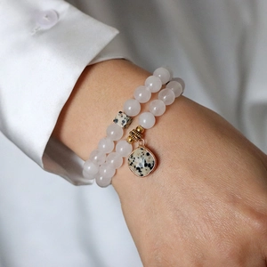 Zweilagiges Perlenarmband mit rosa Steinen und goldgerahmtem Anhänger für Damen am Modell