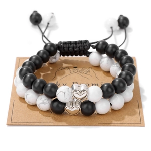 Detail of adjustable couple bracelets with white turquoise beads and heart charms on card