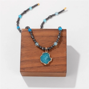 Macro detail of blue agate stone pendant with golden trim on beaded necklace
