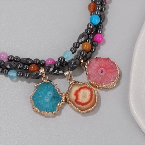 Macro detail of agate stone pendants with gold plating and colorful beaded necklace