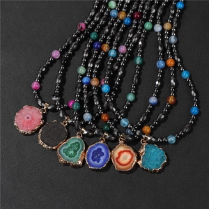 Detailed close-up of colorful natural agate slice pendants with gold edge on black beaded necklaces