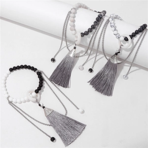 Détail des charms Yin Yang sur bracelets perlés avec texture marbre et glands en soie