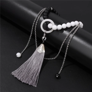 Détail macro du pendentif Yin Yang Tai Chi avec pompon en soie grise et perles dépolies