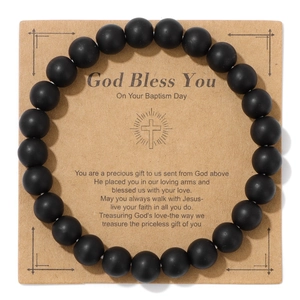 Close-up of matte black natural stone beads bracelet with a God Bless You baptism card