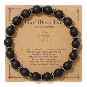Detail of matte black stone beads bracelet with a cross on a religious gift card