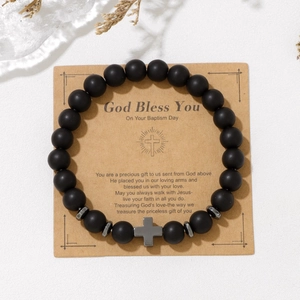 Close-up of black matte stone beads with cross pendant on a baptism gift card