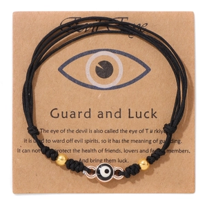 Detail eines handgewebten schwarzen Evil Eye Armbands mit Goldperlen auf Displaykarte