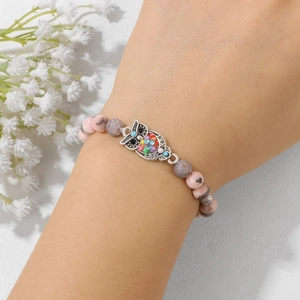 Dettaglio del bracciale con perline zebra rosa e un ciondolo a forma di gufo colorato