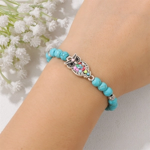 Dettaglio del bracciale di perline turchesi con ciondolo a civetta e accenti colorati