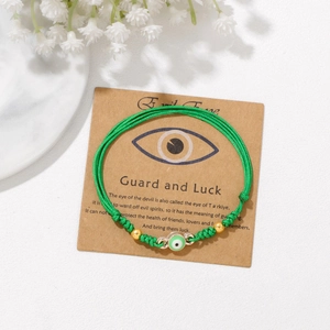 Nahaufnahme grünes geflochtenes Evil Eye Armband mit 18k Goldperlen auf Karte