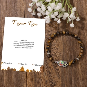 Bracciale di perle occhio di tigre con ciondolo a gufo colorato su sfondo di legno