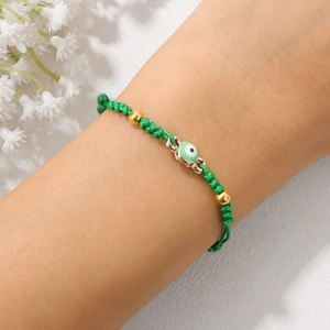 Handgefertigtes grünes Evil Eye Armband mit 18k Goldperlen am Handgelenk