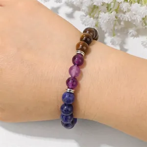 Naturkristallstein-Perlenarmband mit Amethyst und Tigerauge am Handgelenk einer Frau