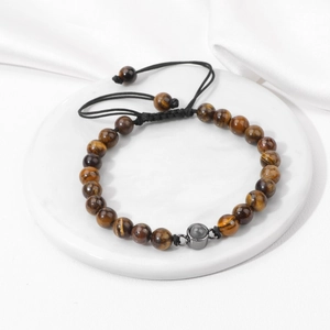 Detailed view of natural tiger eye stone beads with adjustable woven strap on marble