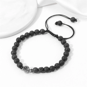 Macro shot of black lava stone beaded bracelet with adjustable woven rope and projector bead