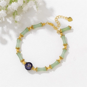 Macro shot of bamboo-shaped jade beads and gold Sagittarius charm on the retro bracelet