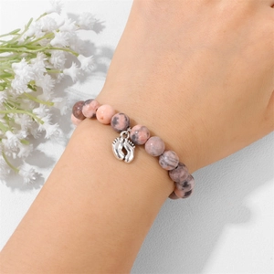 Pink zebra stone beaded bracelet with silver baby footprint charm on female wrist