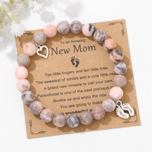 Detail of beaded memorial bracelet with heart and baby feet charms on display card
