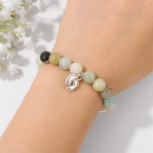 Close-up of beaded emperor stone bracelet with a silver foot charm on a woman's wrist