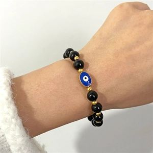 Pulsera de cuentas ojo turco con piedras de ónix negro y espaciadores dorados en la muñeca